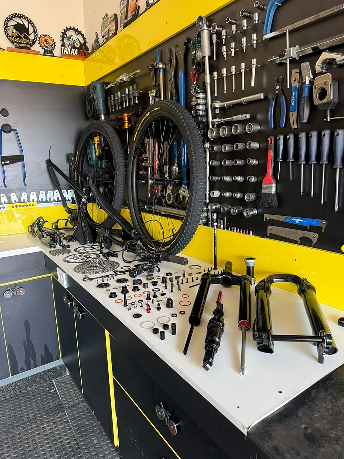 Bancada da oficina Ney Bikes com bicicletas, peças e suspensão