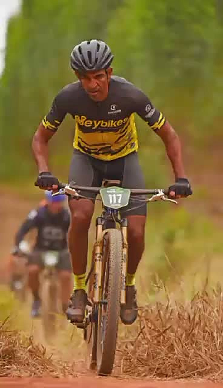 Ney pedalando numa prova de mountain bike com a camisa da Ney Bikes